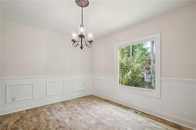 spare room featuring an inviting chandelier, visible vents, and a wainscoted wall
