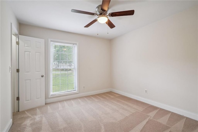 carpeted spare room with baseboards and a ceiling fan