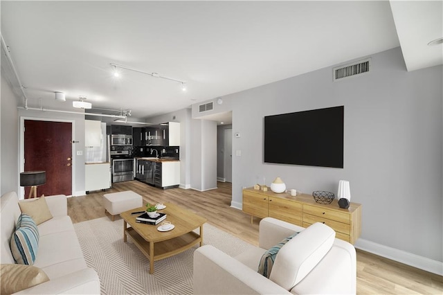 living room featuring track lighting, sink, and light hardwood / wood-style flooring