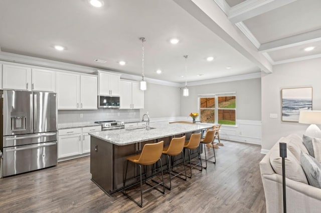 kitchen featuring appliances with stainless steel finishes, light stone counters, white cabinetry, and an island with sink