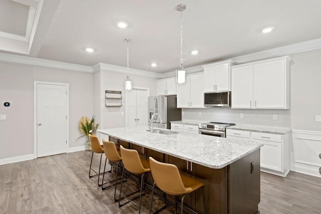 kitchen featuring appliances with stainless steel finishes, hardwood / wood-style flooring, white cabinets, and an island with sink