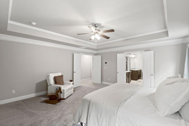 bedroom with ceiling fan, a raised ceiling, crown molding, ensuite bathroom, and light colored carpet