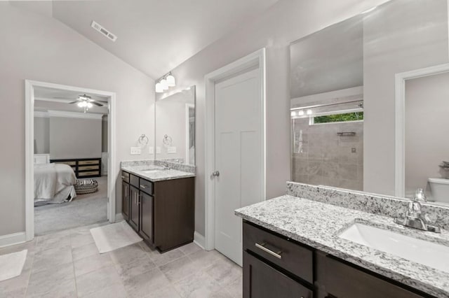 bathroom with ceiling fan, vanity, lofted ceiling, a tile shower, and toilet