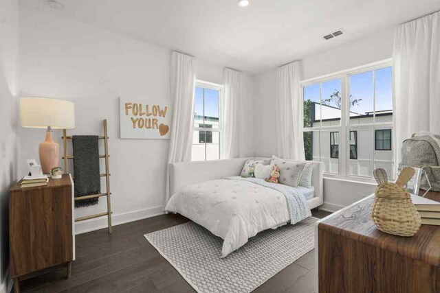 bedroom with multiple windows and dark hardwood / wood-style floors