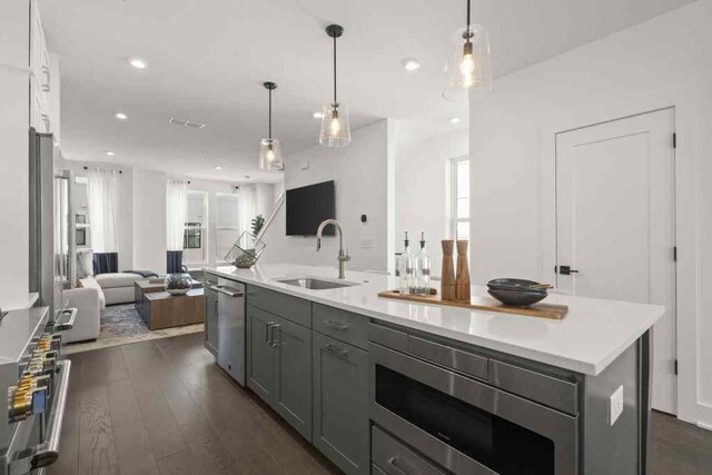 kitchen with a kitchen island, dark hardwood / wood-style flooring, sink, decorative light fixtures, and stainless steel appliances