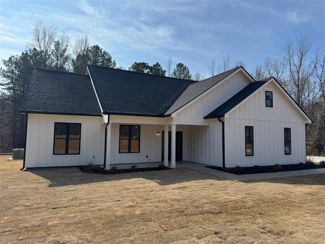 view of front of house with board and batten siding, a front yard, and a shingled roof