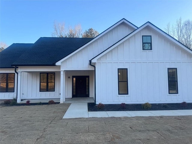 modern farmhouse featuring a porch, board and batten siding, and roof with shingles