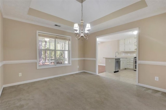 carpeted empty room with crown molding, an inviting chandelier, a tray ceiling, and sink