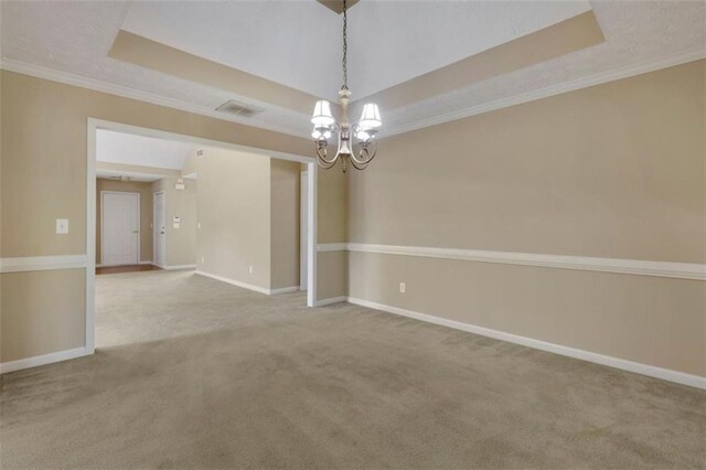 empty room featuring a tray ceiling, light carpet, and crown molding