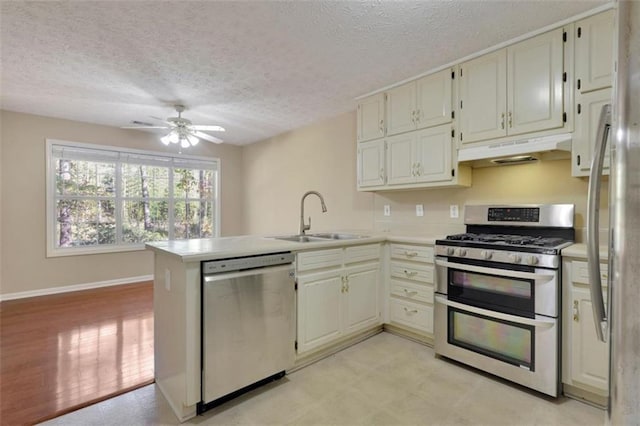 kitchen featuring kitchen peninsula, stainless steel appliances, sink, ceiling fan, and a textured ceiling