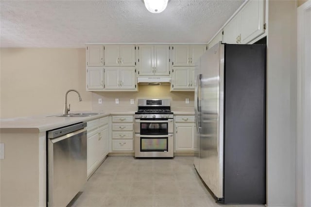 kitchen with appliances with stainless steel finishes, sink, a textured ceiling, kitchen peninsula, and white cabinets