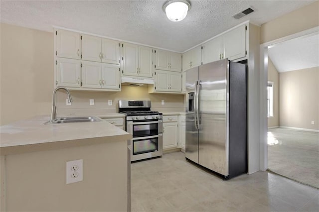 kitchen with kitchen peninsula, sink, a textured ceiling, appliances with stainless steel finishes, and white cabinets