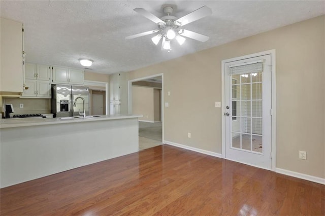 kitchen with white cabinets, light hardwood / wood-style flooring, stainless steel fridge, and a textured ceiling