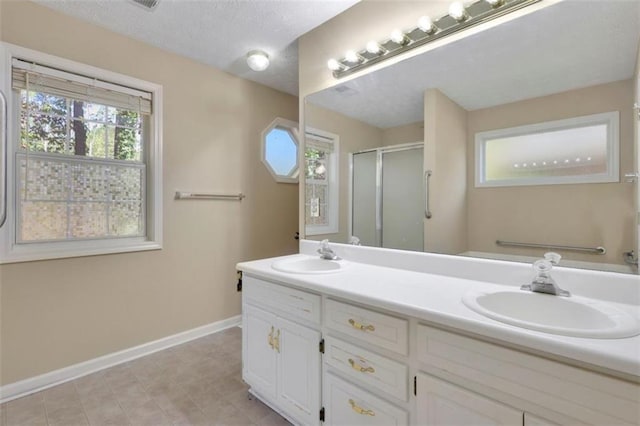 bathroom featuring plenty of natural light, a textured ceiling, vanity, and walk in shower