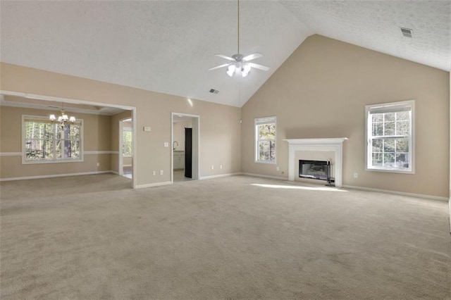 unfurnished living room featuring ceiling fan with notable chandelier, high vaulted ceiling, a textured ceiling, and light colored carpet