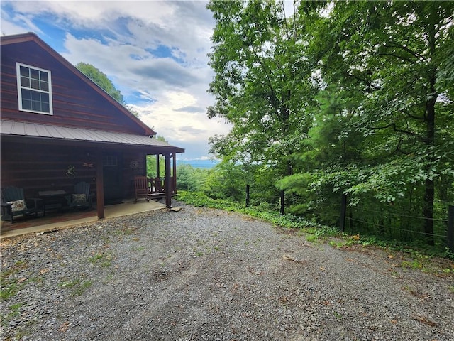 view of side of home featuring metal roof and driveway