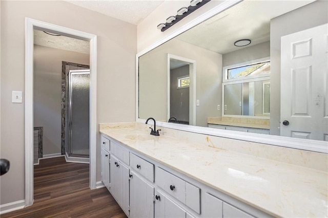 full bath with baseboards, vanity, a stall shower, and wood finished floors