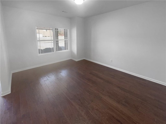 unfurnished room with visible vents, baseboards, and dark wood finished floors