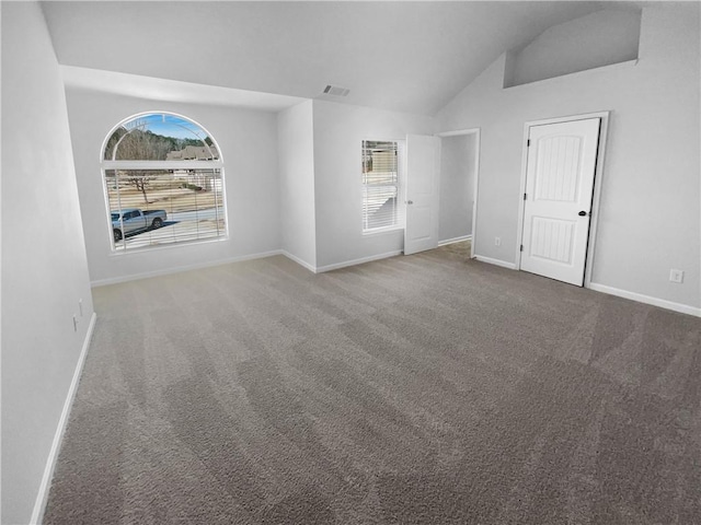 carpeted spare room with visible vents, vaulted ceiling, and baseboards