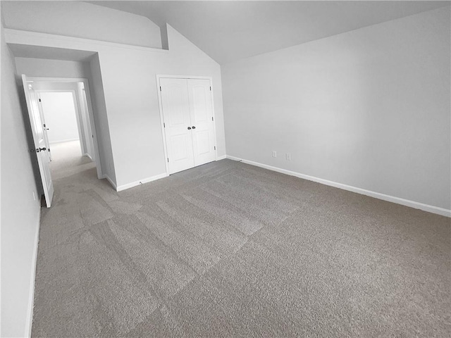 unfurnished bedroom with carpet, a closet, vaulted ceiling, and baseboards