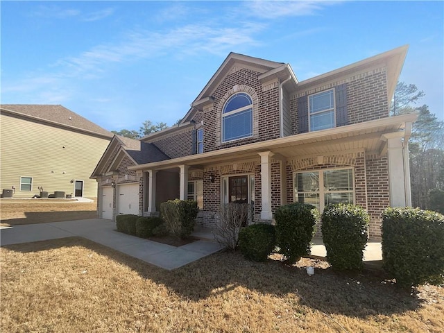 traditional-style home featuring a garage, a porch, concrete driveway, and brick siding