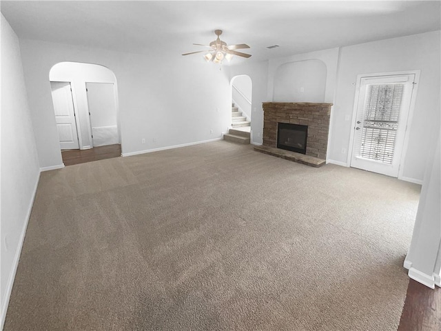 unfurnished living room with arched walkways, a fireplace, and carpet