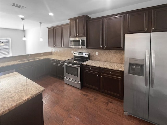 kitchen featuring dark brown cabinetry, decorative backsplash, dark wood-type flooring, stainless steel appliances, and a sink