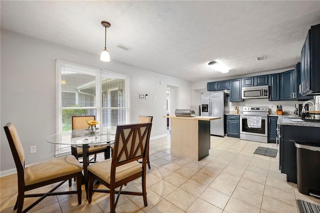 1328 Hidden Hills Pkwy, Stone Mountain, GA 30088 - kitchen with appliances with stainless steel finishes, a center island, light countertops, light tile patterned flooring, and a textured ceiling