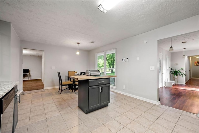 1328 Hidden Hills Pkwy, Stone Mountain, GA 30088 - kitchen featuring dishwashing machine, light tile patterned flooring, a textured ceiling, hanging light fixtures, and a kitchen island