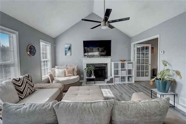 living room with vaulted ceiling, ceiling fan, a healthy amount of sunlight, and hardwood / wood-style floors