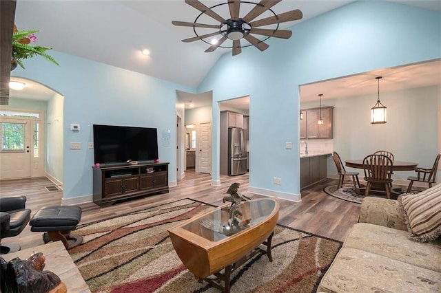 562 Yonah Lake Dr, Sautee Nacoochee, GA 30572 - living room featuring a ceiling fan, wood finished floors, high vaulted ceiling, baseboards, and arched walkways