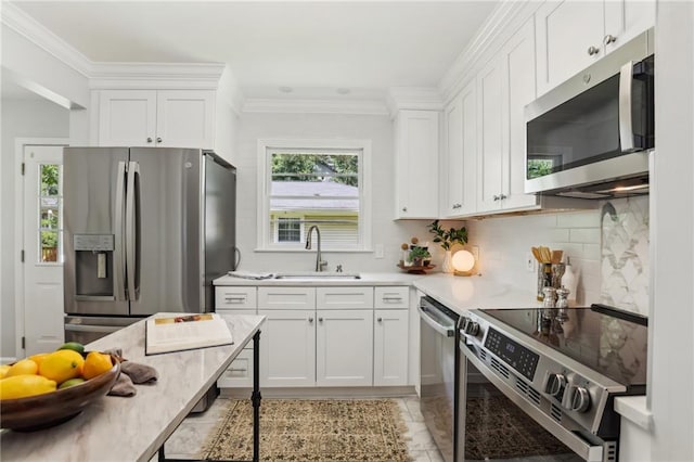 kitchen with stainless steel appliances, light countertops, white cabinetry, and a sink