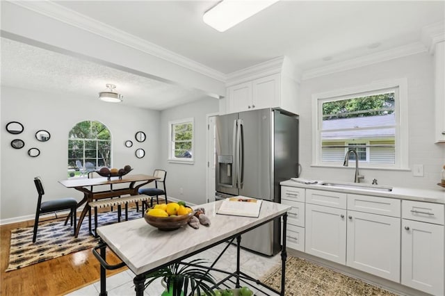 kitchen featuring white cabinets, light countertops, a sink, and stainless steel refrigerator with ice dispenser