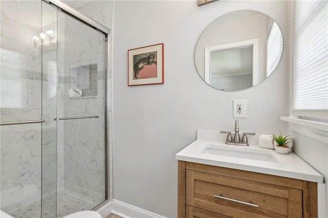 bathroom featuring a marble finish shower, baseboards, and vanity