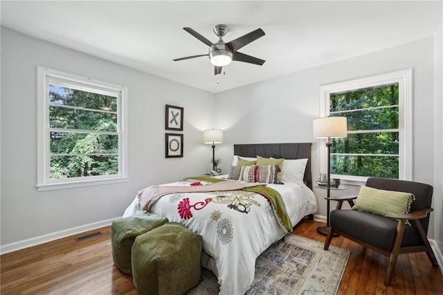 bedroom featuring ceiling fan, wood finished floors, visible vents, and baseboards