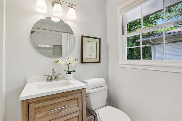 bathroom featuring toilet, vanity, and a shower with curtain