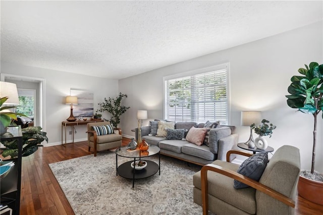 living room featuring a textured ceiling, baseboards, dark wood-style flooring, and a wealth of natural light