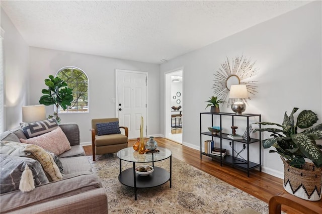 living room with a textured ceiling, dark wood-type flooring, and baseboards