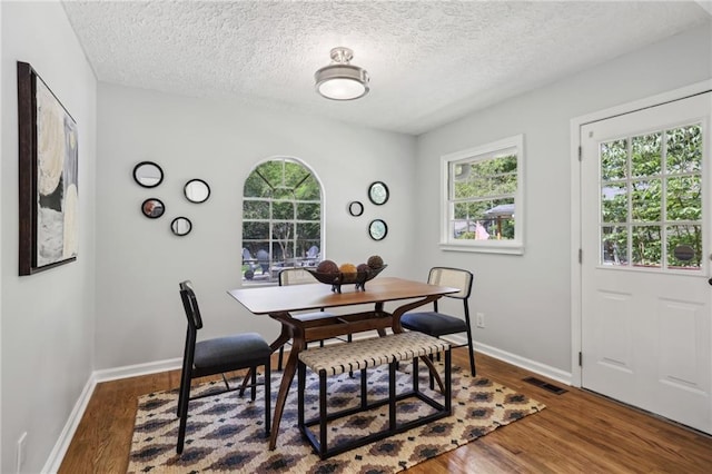 dining area featuring plenty of natural light, baseboards, and dark wood-type flooring