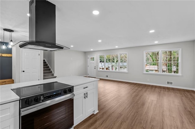 kitchen featuring hanging light fixtures, range with electric stovetop, a wealth of natural light, island exhaust hood, and white cabinets