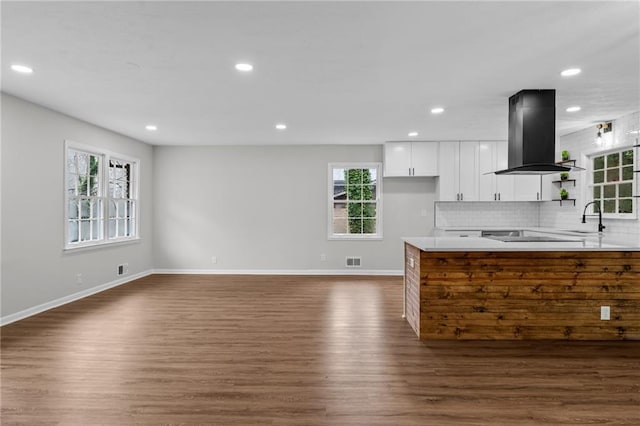 kitchen with island range hood, sink, white cabinets, decorative backsplash, and dark wood-type flooring