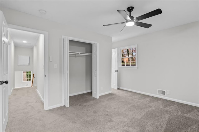 unfurnished bedroom featuring ceiling fan, light colored carpet, and a closet