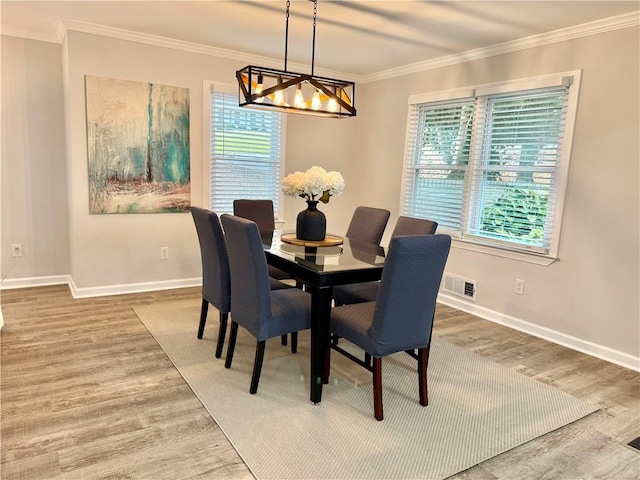 dining space featuring hardwood / wood-style flooring, an inviting chandelier, and ornamental molding