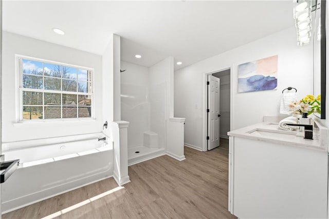 bathroom with a garden tub, a stall shower, wood finished floors, recessed lighting, and vanity