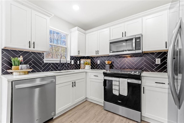 kitchen with stainless steel appliances, light countertops, light wood-style floors, and a sink