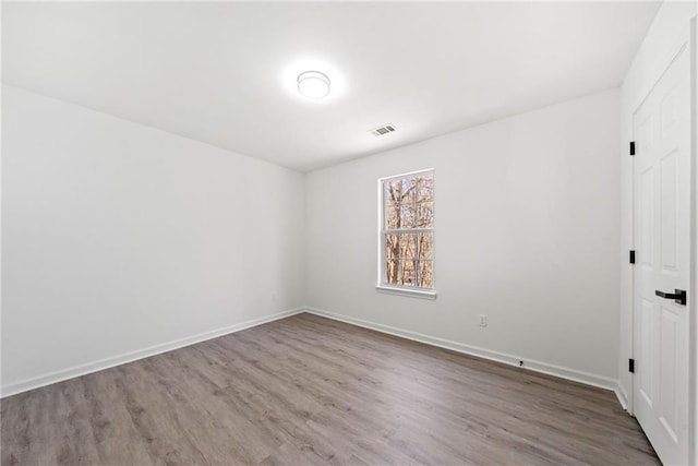 unfurnished room featuring visible vents, baseboards, and wood finished floors