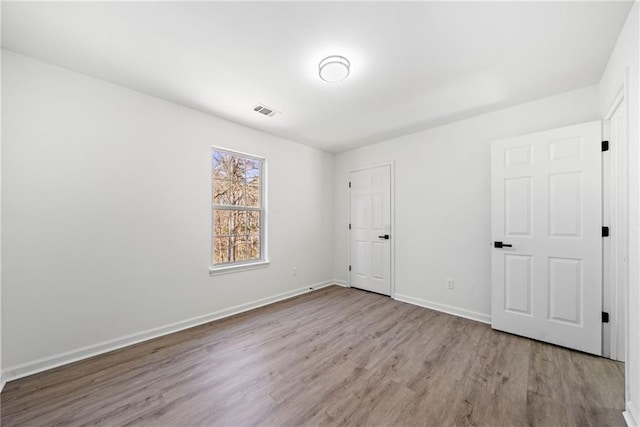 unfurnished bedroom with wood finished floors, visible vents, and baseboards