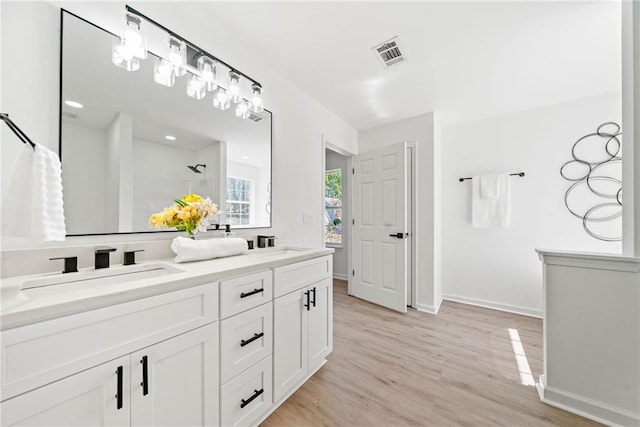 bathroom with visible vents, a sink, wood finished floors, a shower with shower curtain, and double vanity