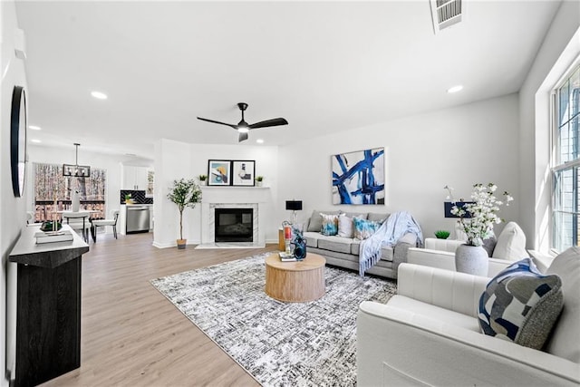 living room featuring visible vents, ceiling fan, a fireplace with flush hearth, recessed lighting, and light wood-style flooring