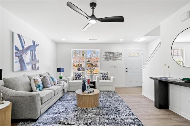 living room with ceiling fan, visible vents, baseboards, and wood finished floors